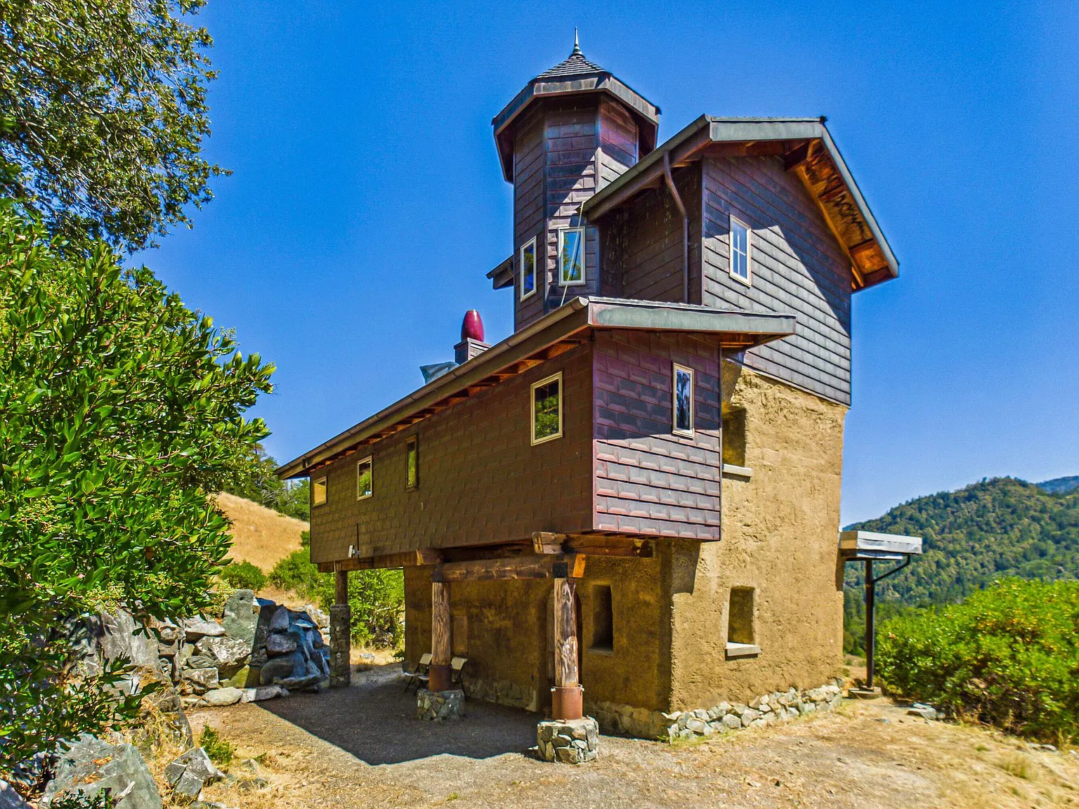An aerial view of the home's distinctive tower design amid oak woodlands and rolling hills