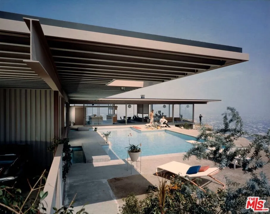 The pool and terrace in daylight, the glass wing of the house along one side