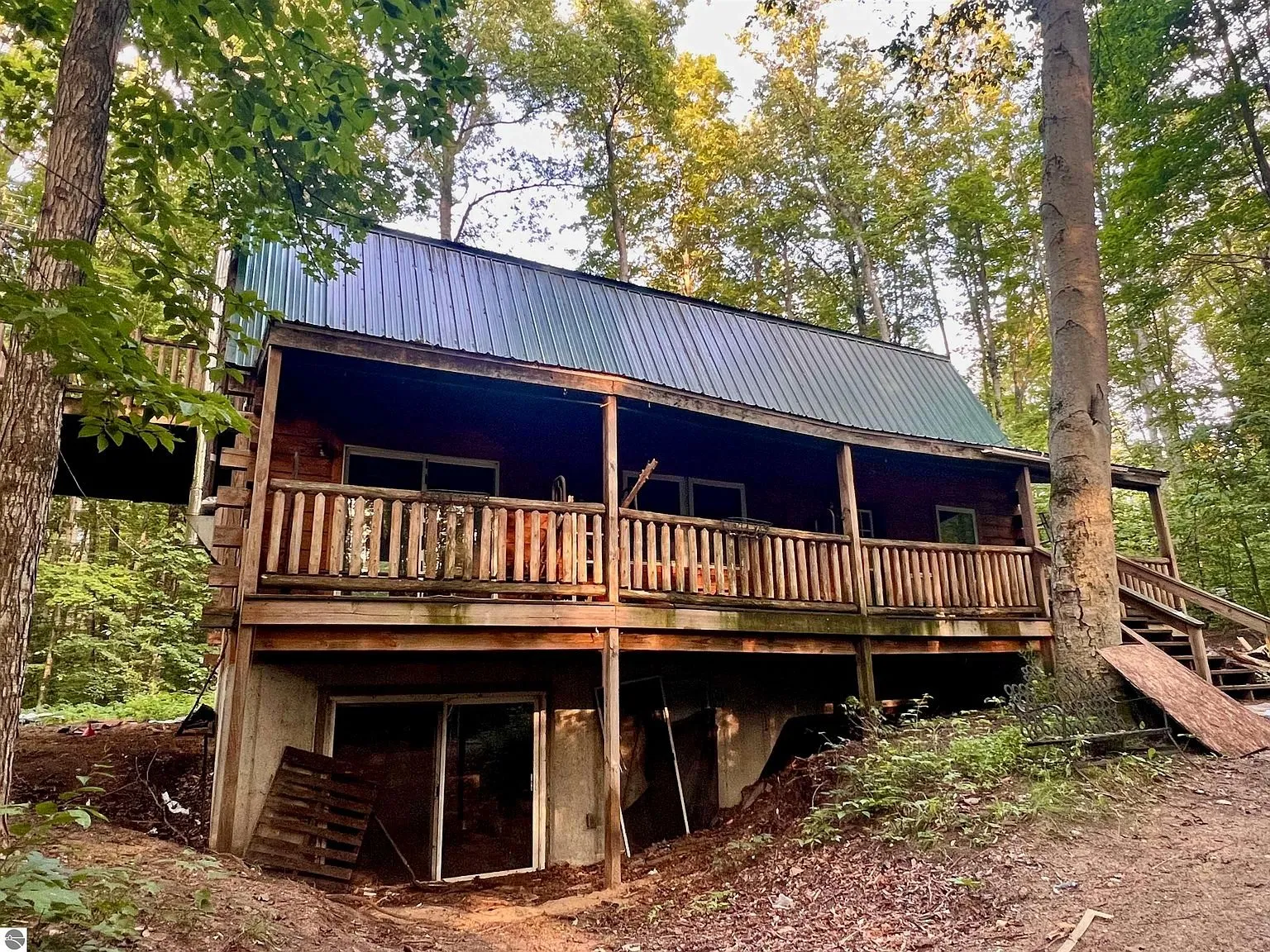 The front of the cabin with the covered porch on log posts and the walkout below