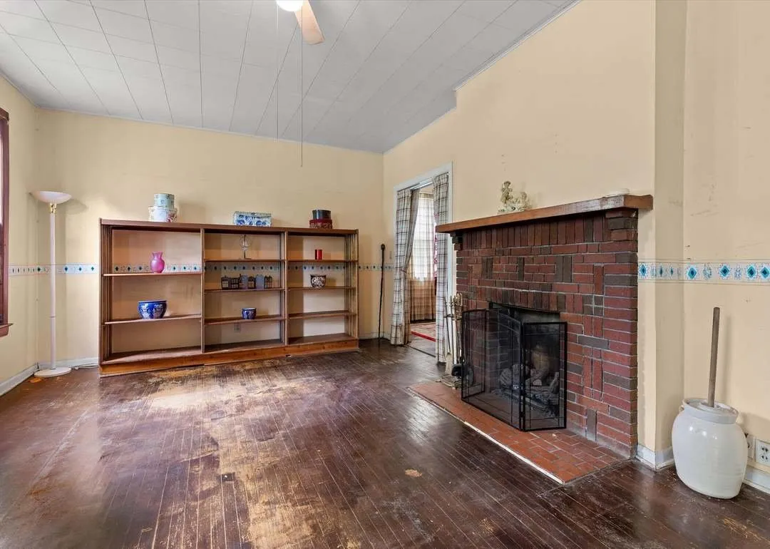 The living room with a brick fireplace and hardwood floors
