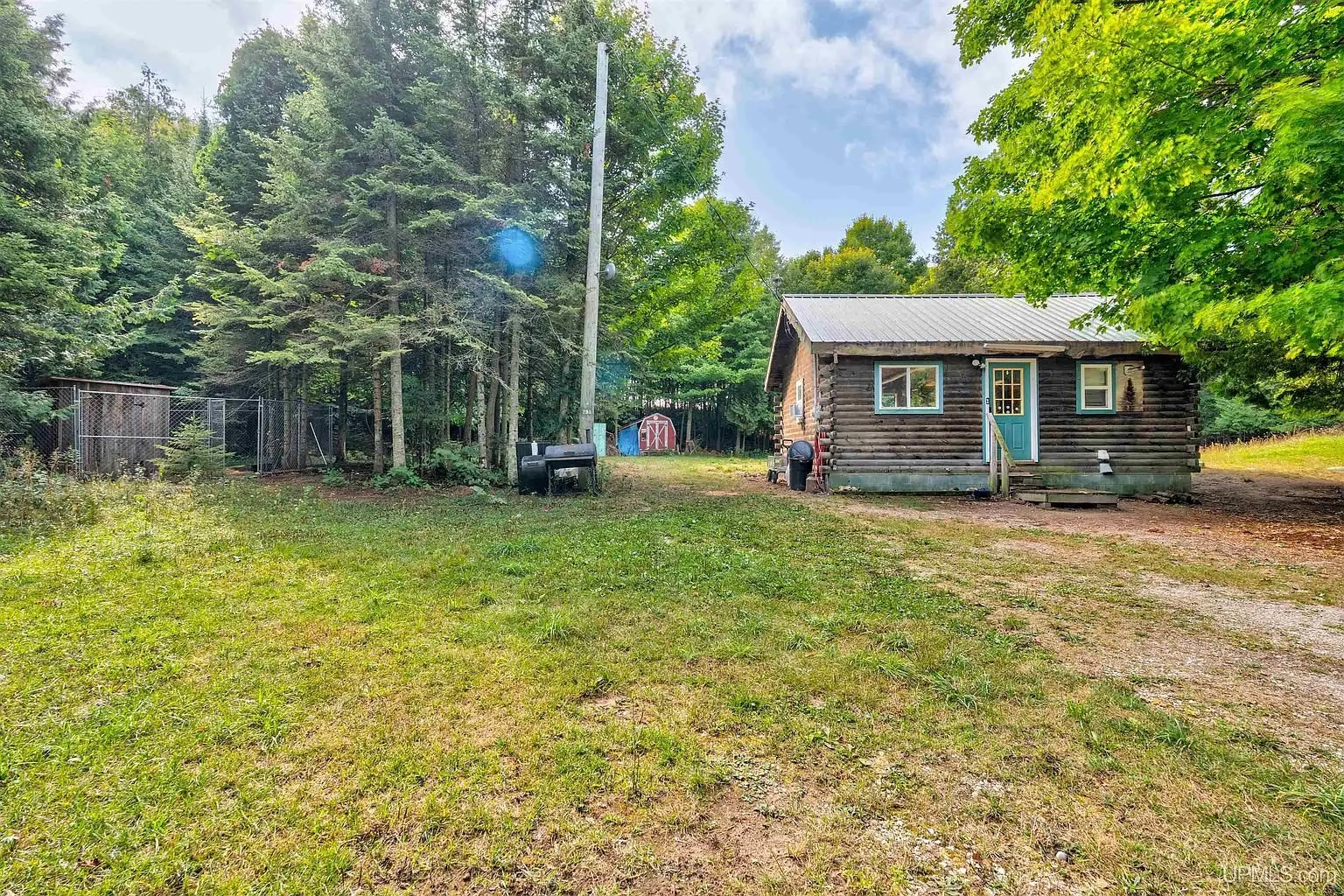 The cottage across the mown yard with the red shed beyond