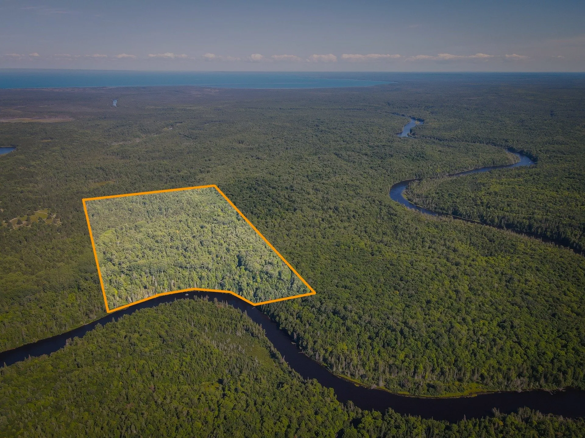 Aerial with the listing's outline of the 72-acre parcel drawn in orange beside the river bend