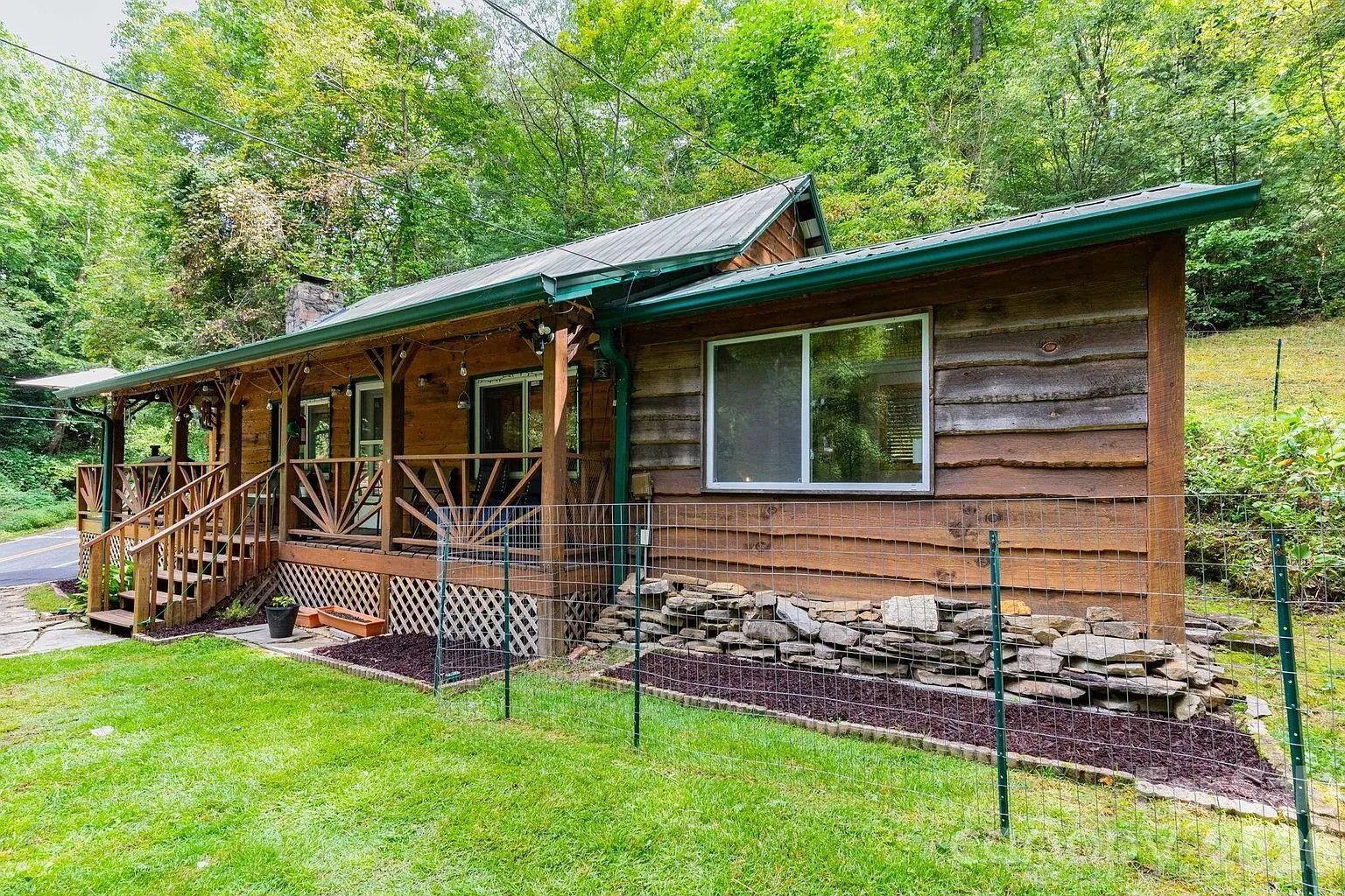 The cottage from the side with the porch rail and the stone skirt