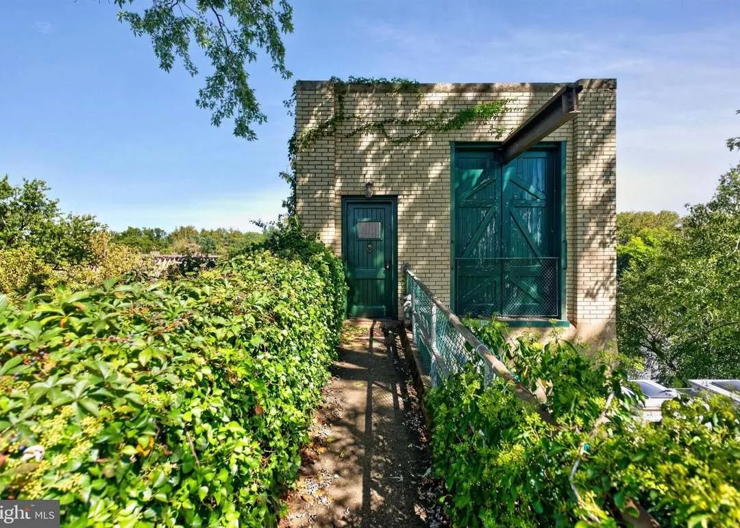 The building's entry door framed by green shutters and climbing vines