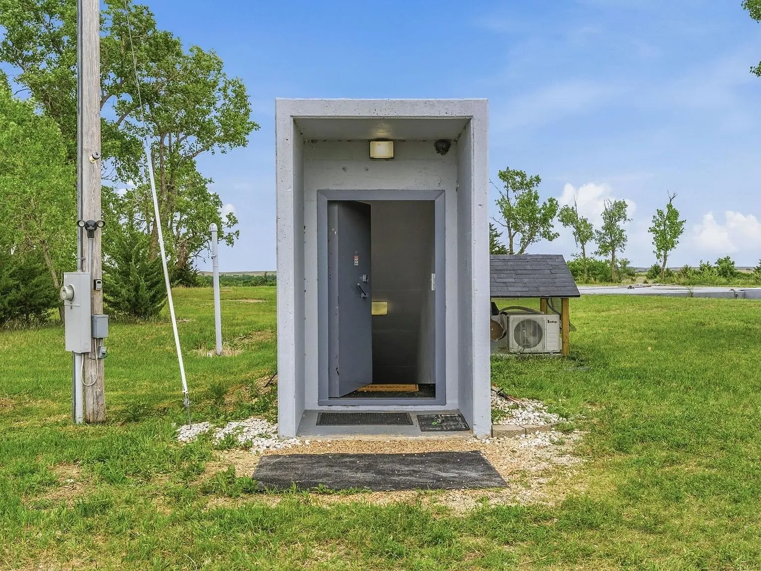 A second concrete entry pod with its steel door, utility unit beside it