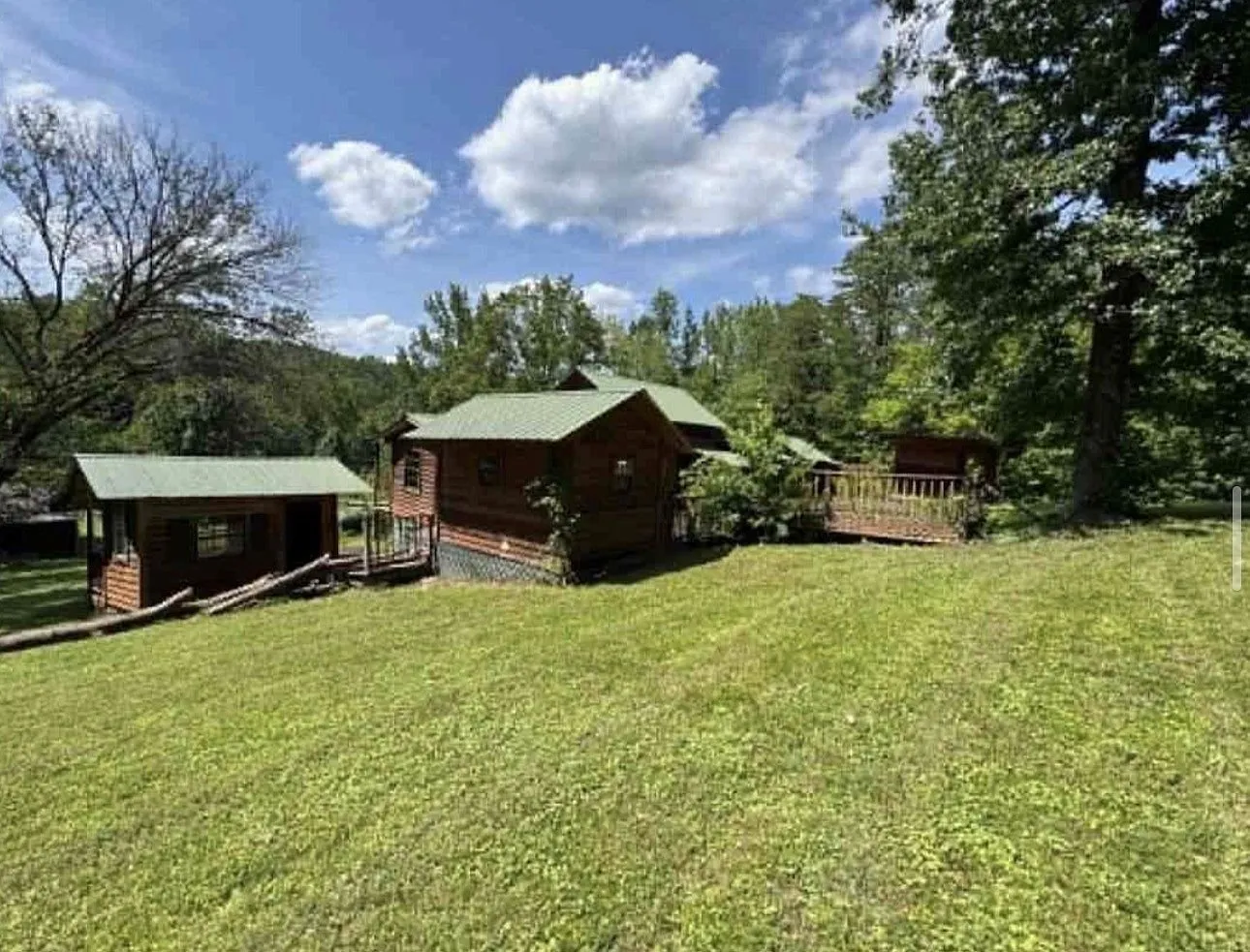 The cabin and outbuilding from a wider angle across the grass