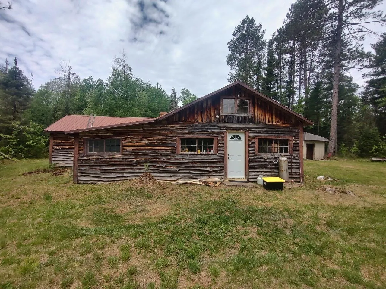 The front of the log camp with the entry door and the row of windows