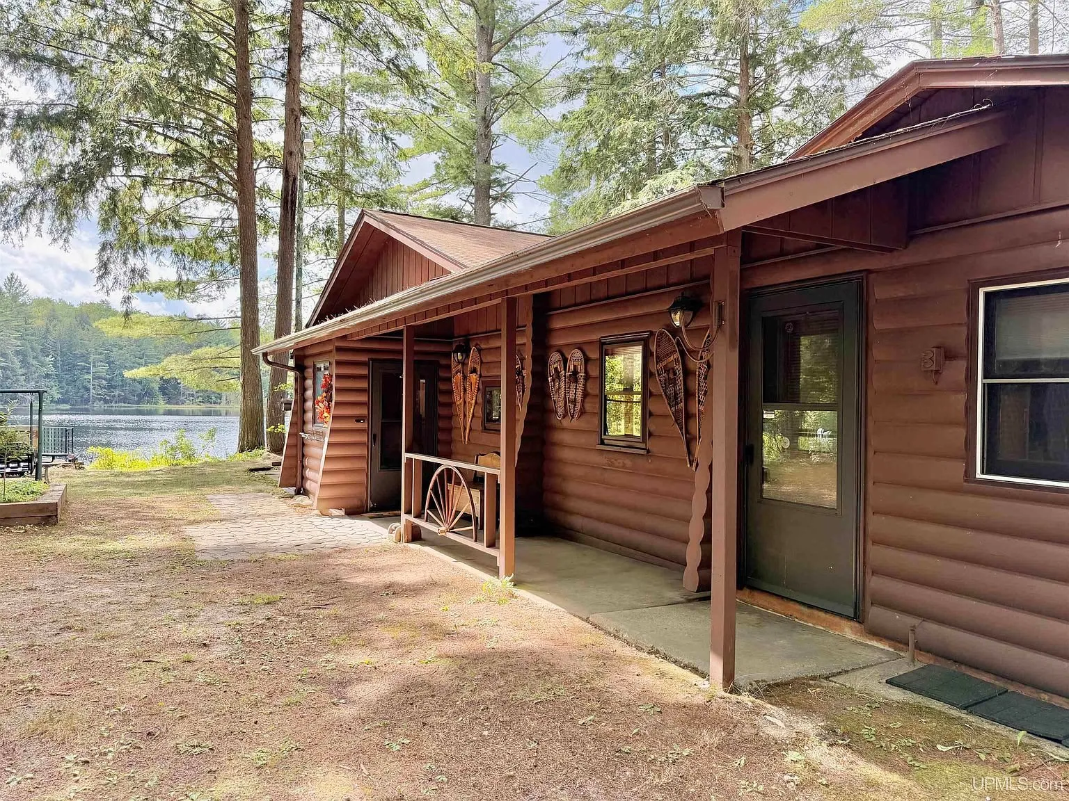 The front of the log cabin under the pines with the lake behind it