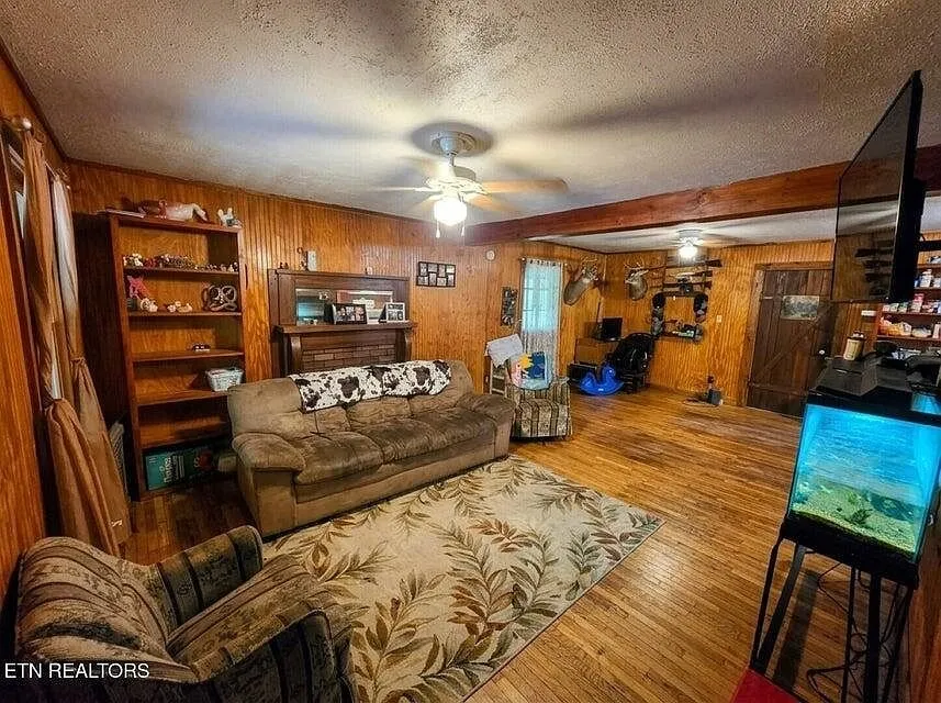The open living and dining area with hardwood floors and wood-paneled walls