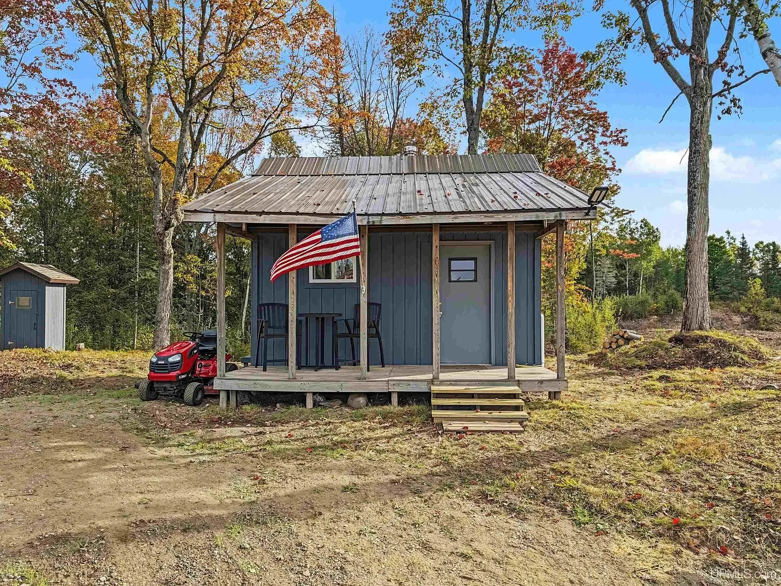 The camp in its clearing from a different angle, flag on the porch post