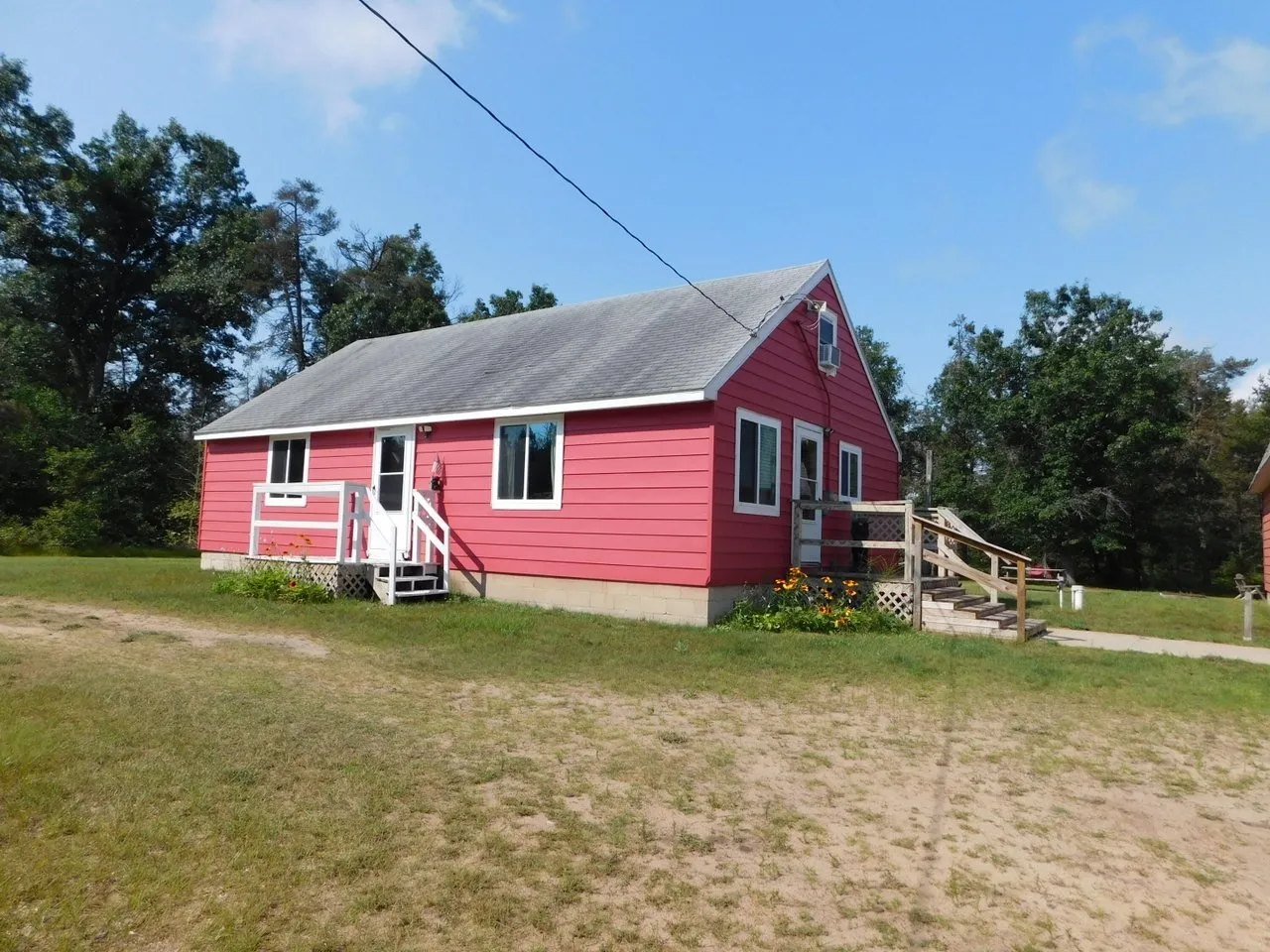 The cabin from the driveway, white steps up to the entry door