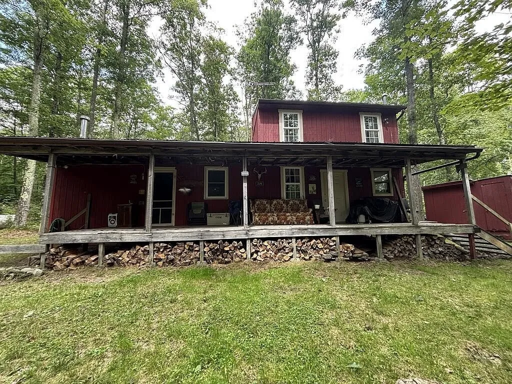 The red cabin with its covered porch and firewood stacked along the front