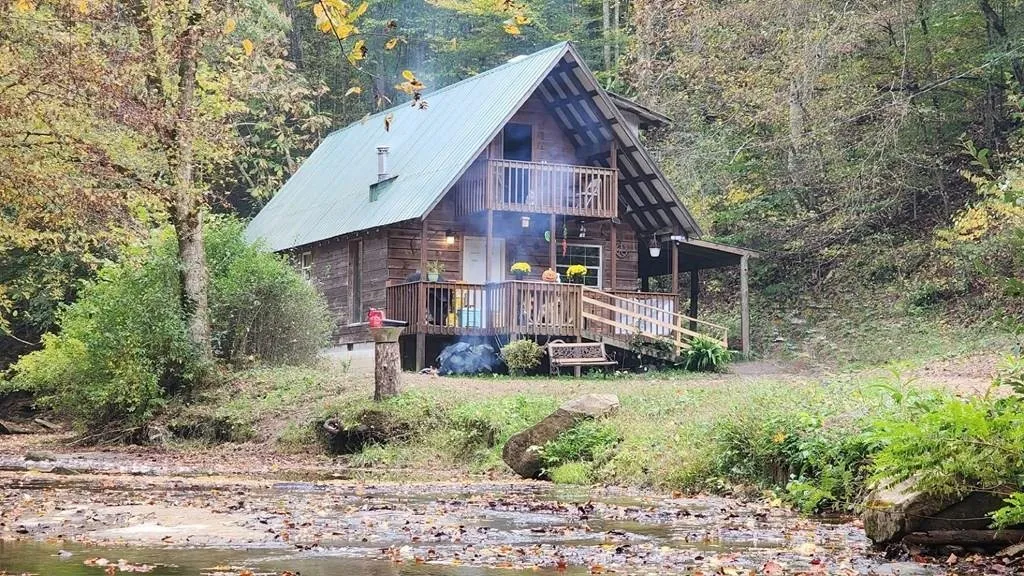 The cabin across the creek in autumn, the two-story front with its balcony