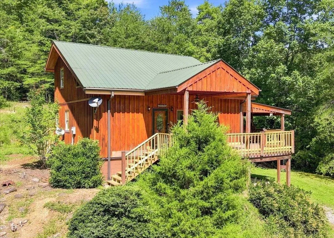 The same cabin from a second angle, surrounded by dense woods