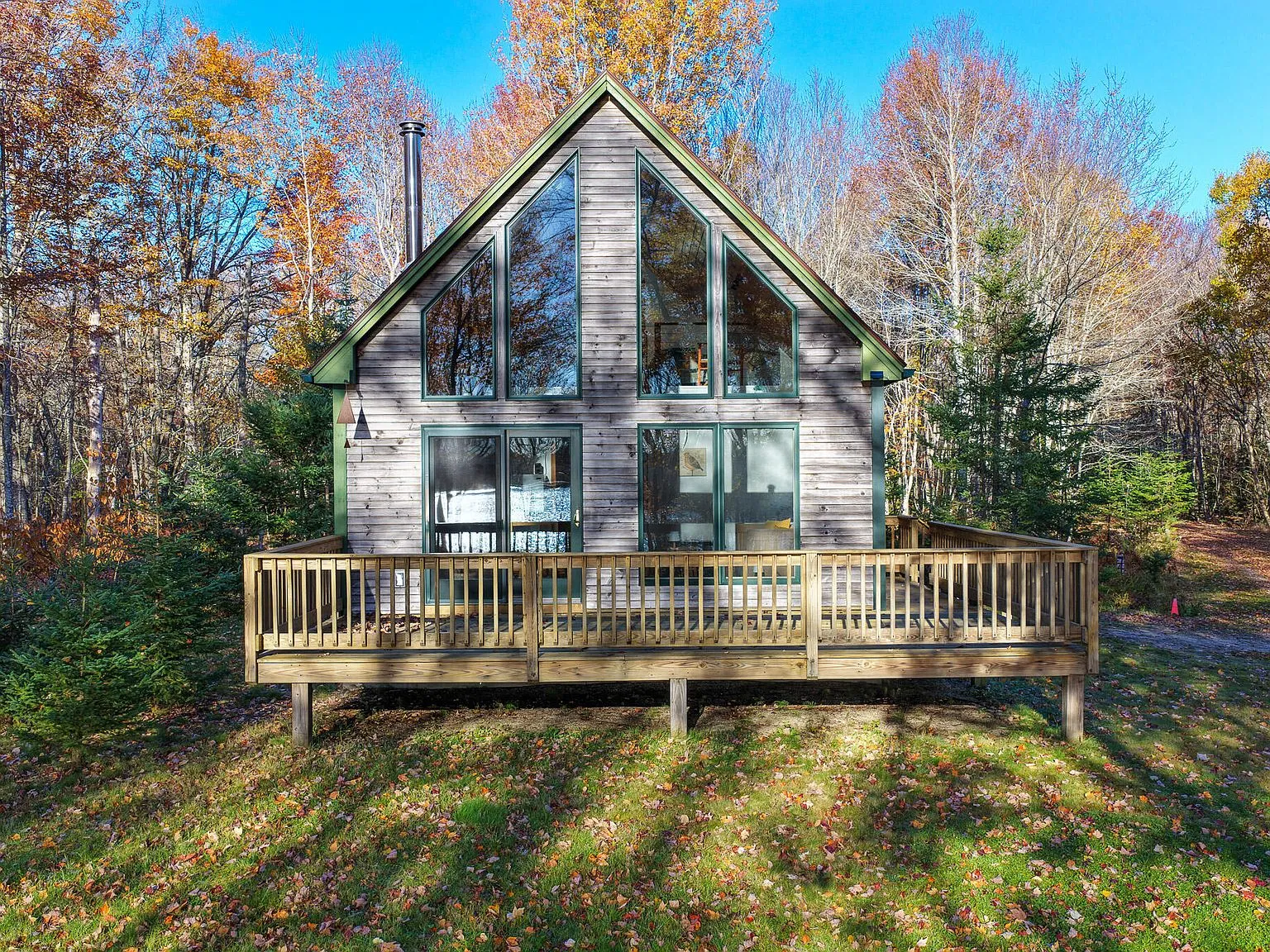 The wraparound deck's wood railing overlooking the wooded lot in autumn