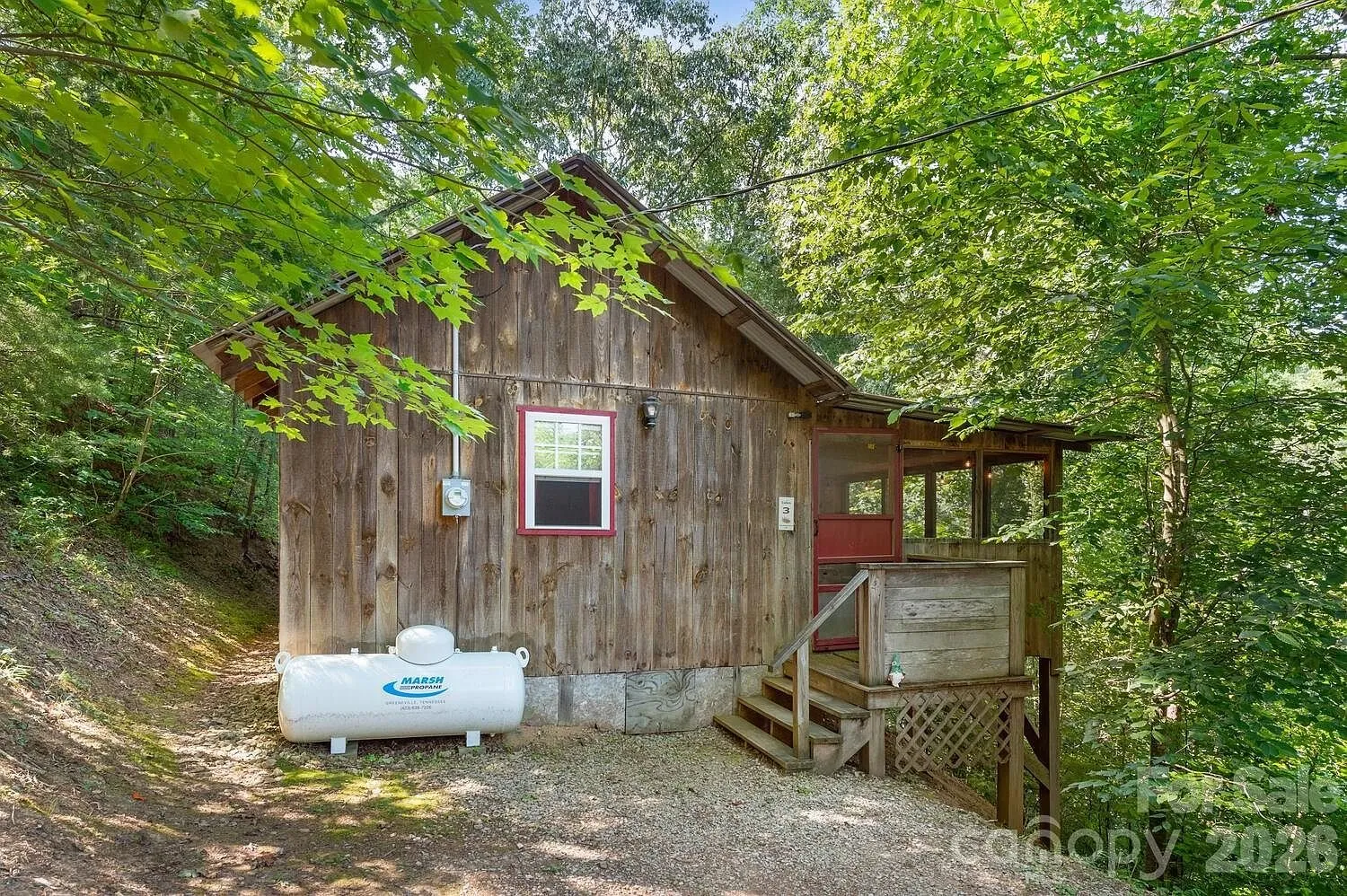 The side of the cabin with the propane tank and the steps to the porch