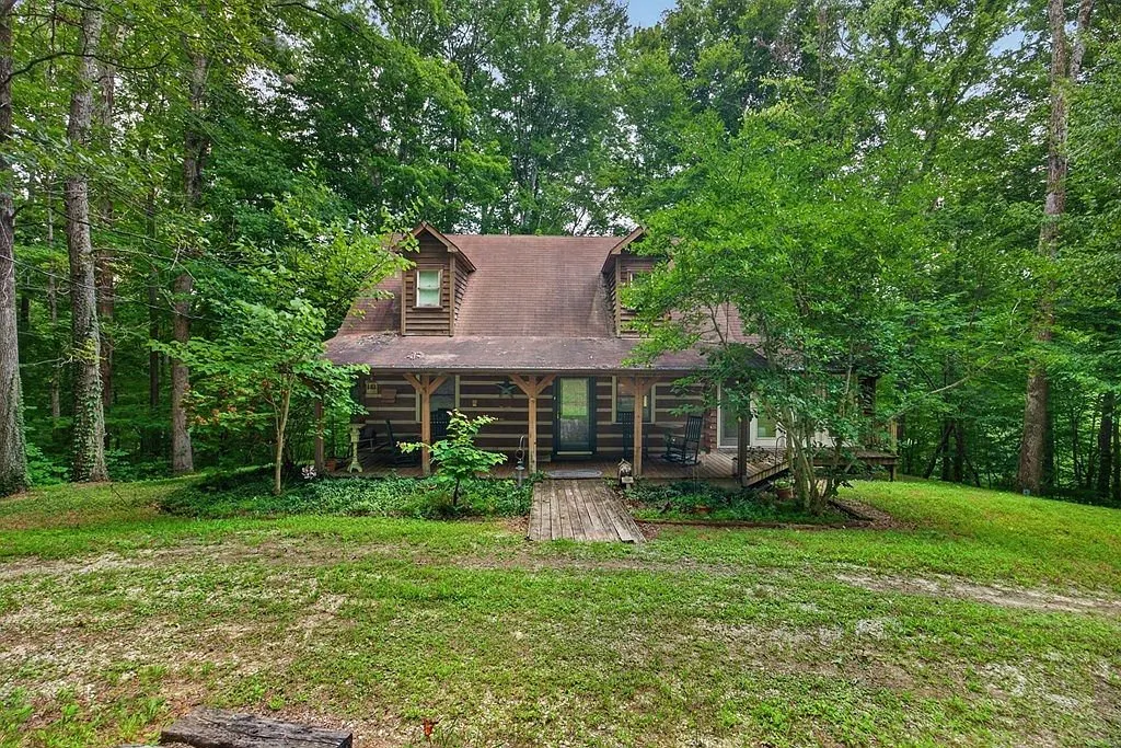 The log home seen across the open lawn, upper dormer windows visible