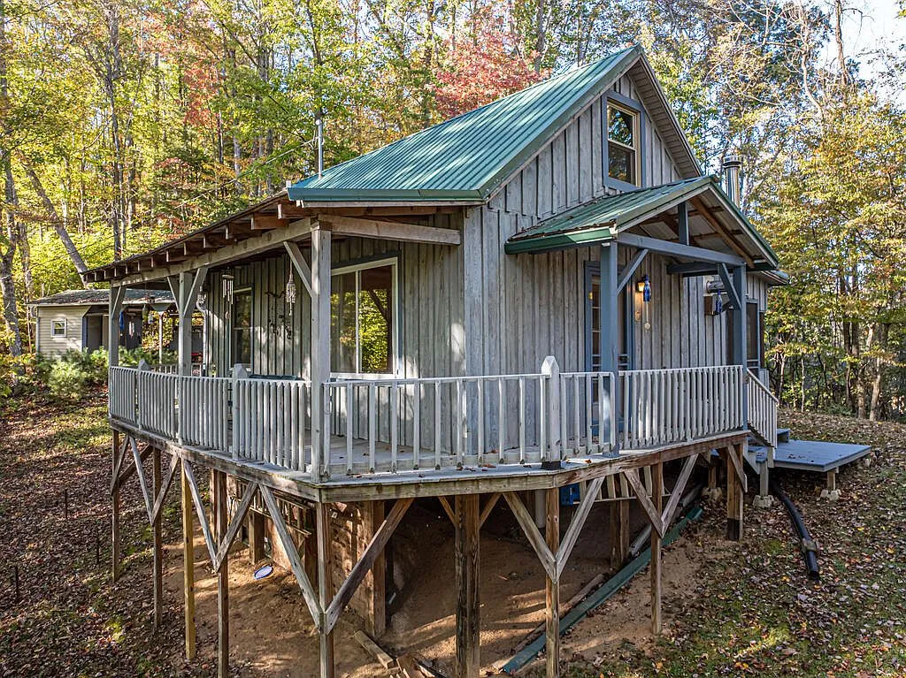 The cabin seen from the side, with the second-level balcony and wraparound porch