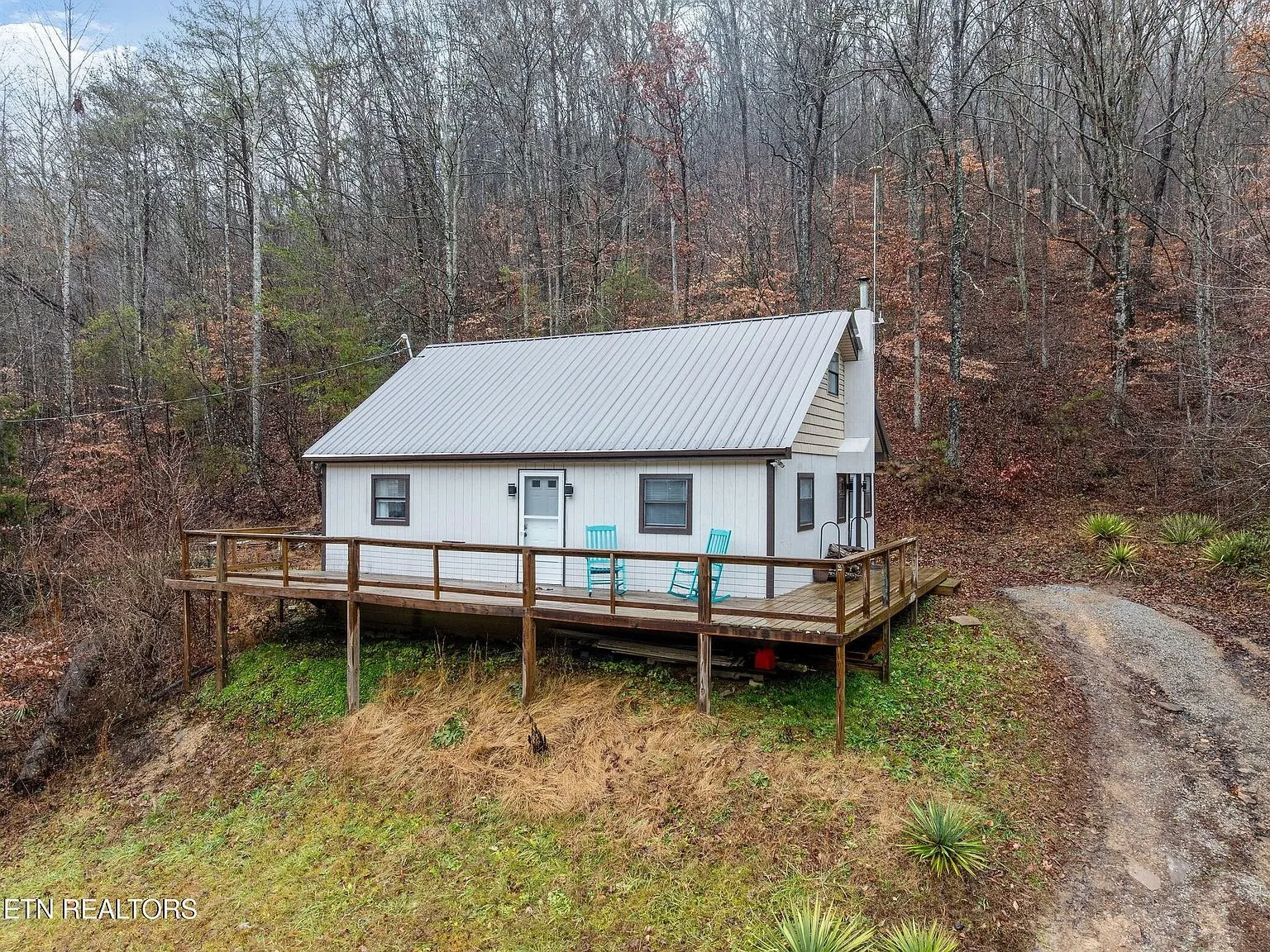 The cottage and deck seen from the gravel driveway approach