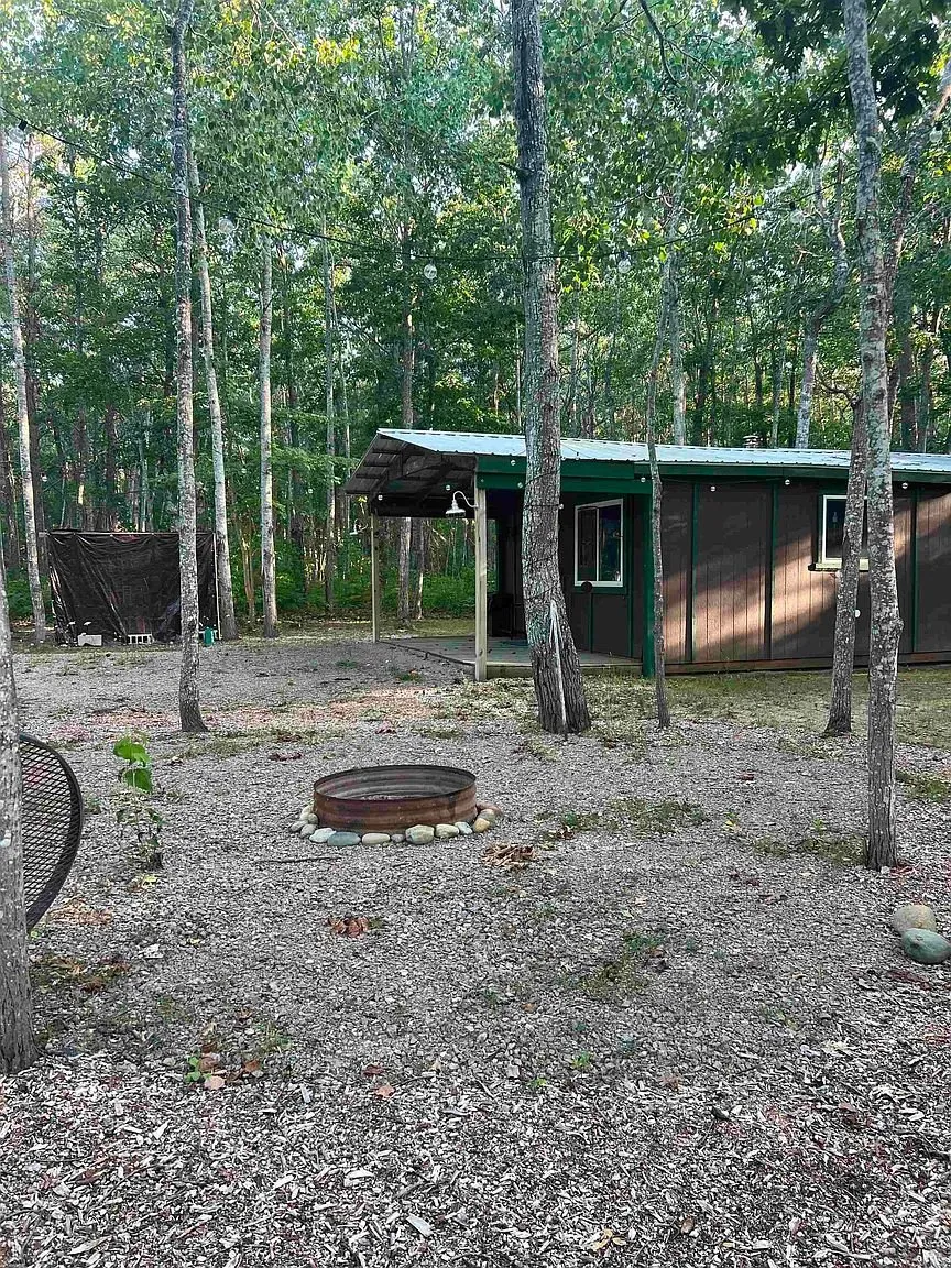 The fire ring in the yard with the cabin and its porch beyond