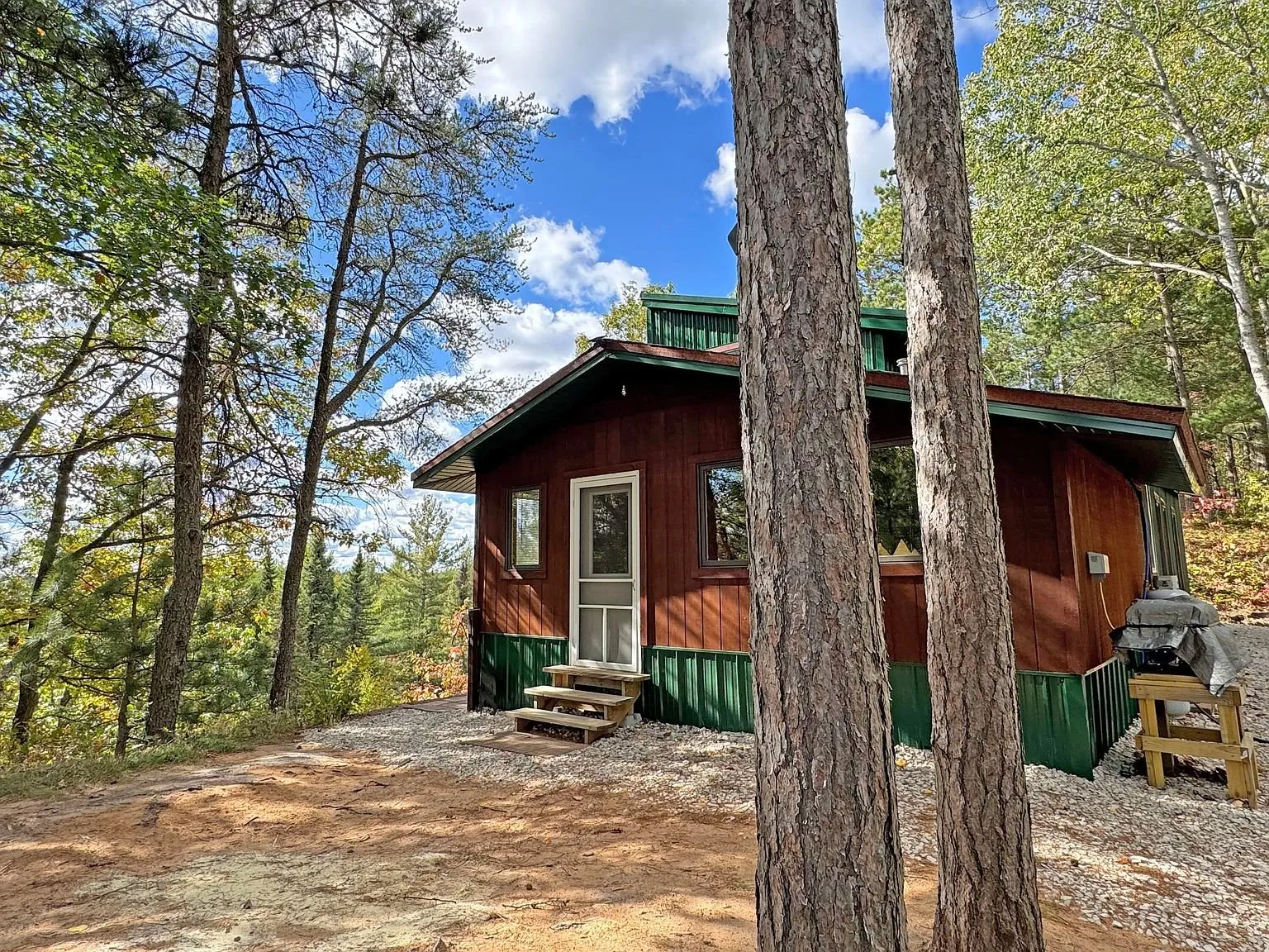 The cabin from the trees, deck running along the near side