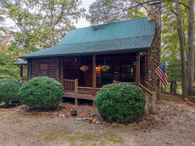 The cabin's covered front porch with landscaped shrubs along the base