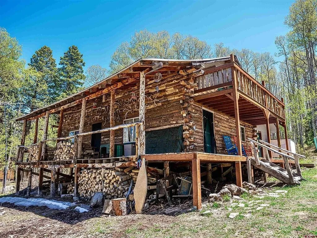 The cabin from below with the firewood stacked under the deck