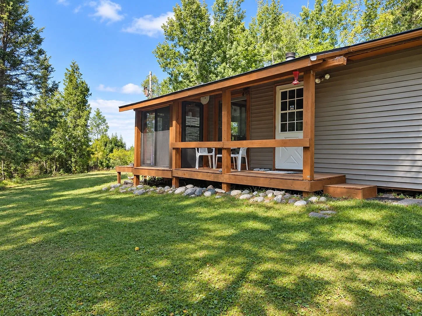 The side of the cabin with the covered porch and the chairs