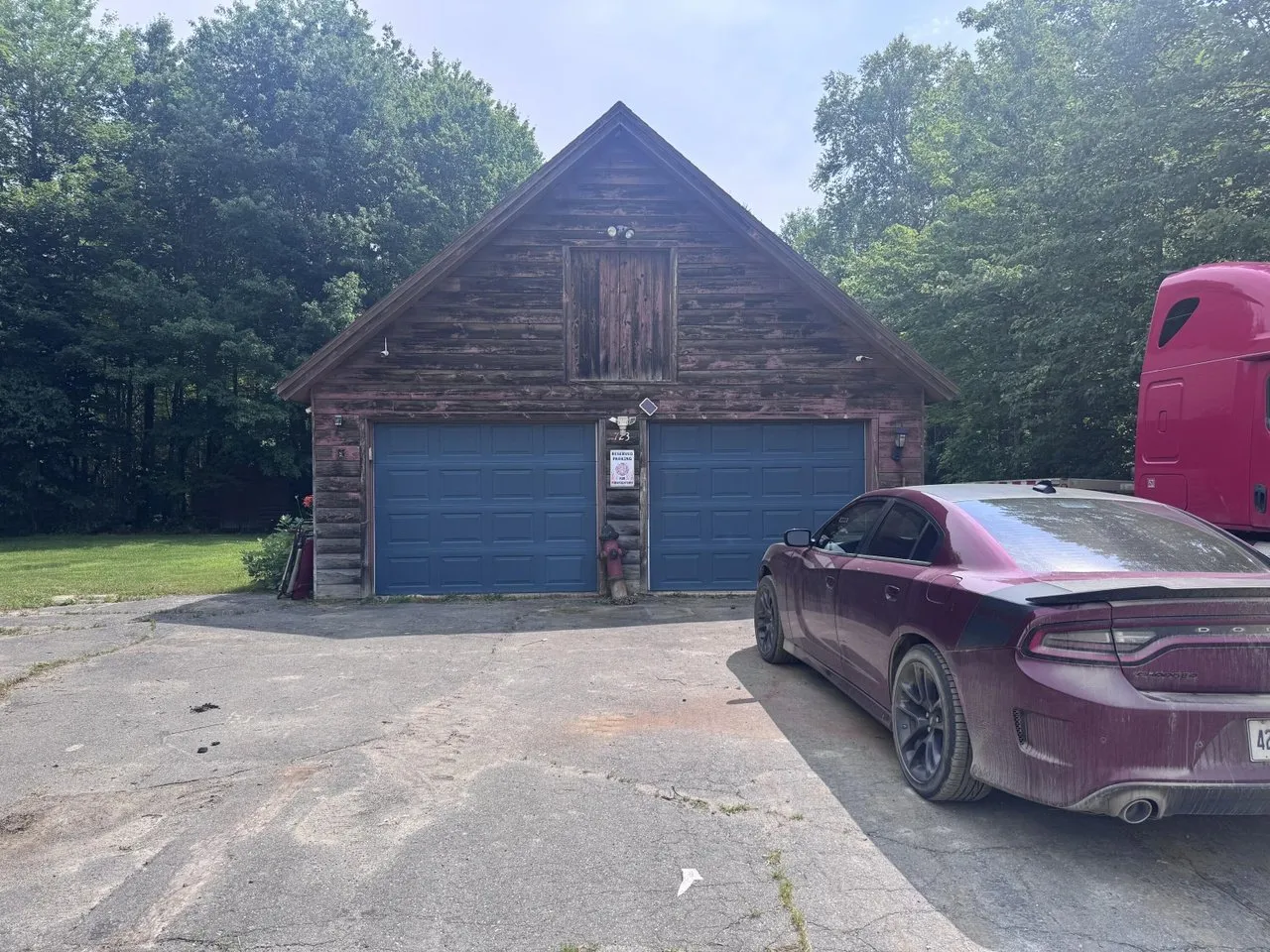 The garage with its two blue doors, the car in the drive and the truck cab beside it