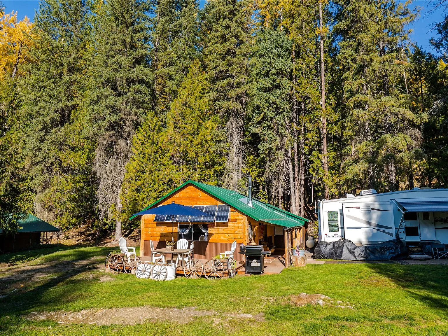The cabin's covered porch with rooftop solar panels, patio furniture and an antique wagon wheel