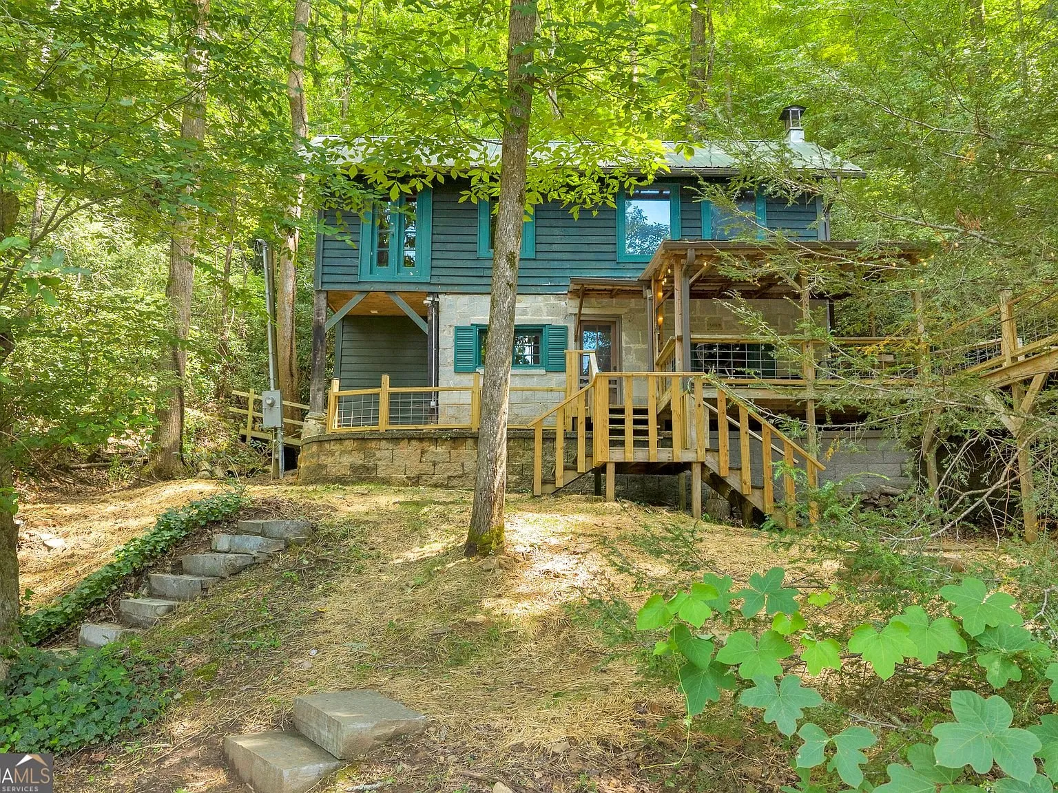 The cabin's elevated entry stairs and deck among the trees