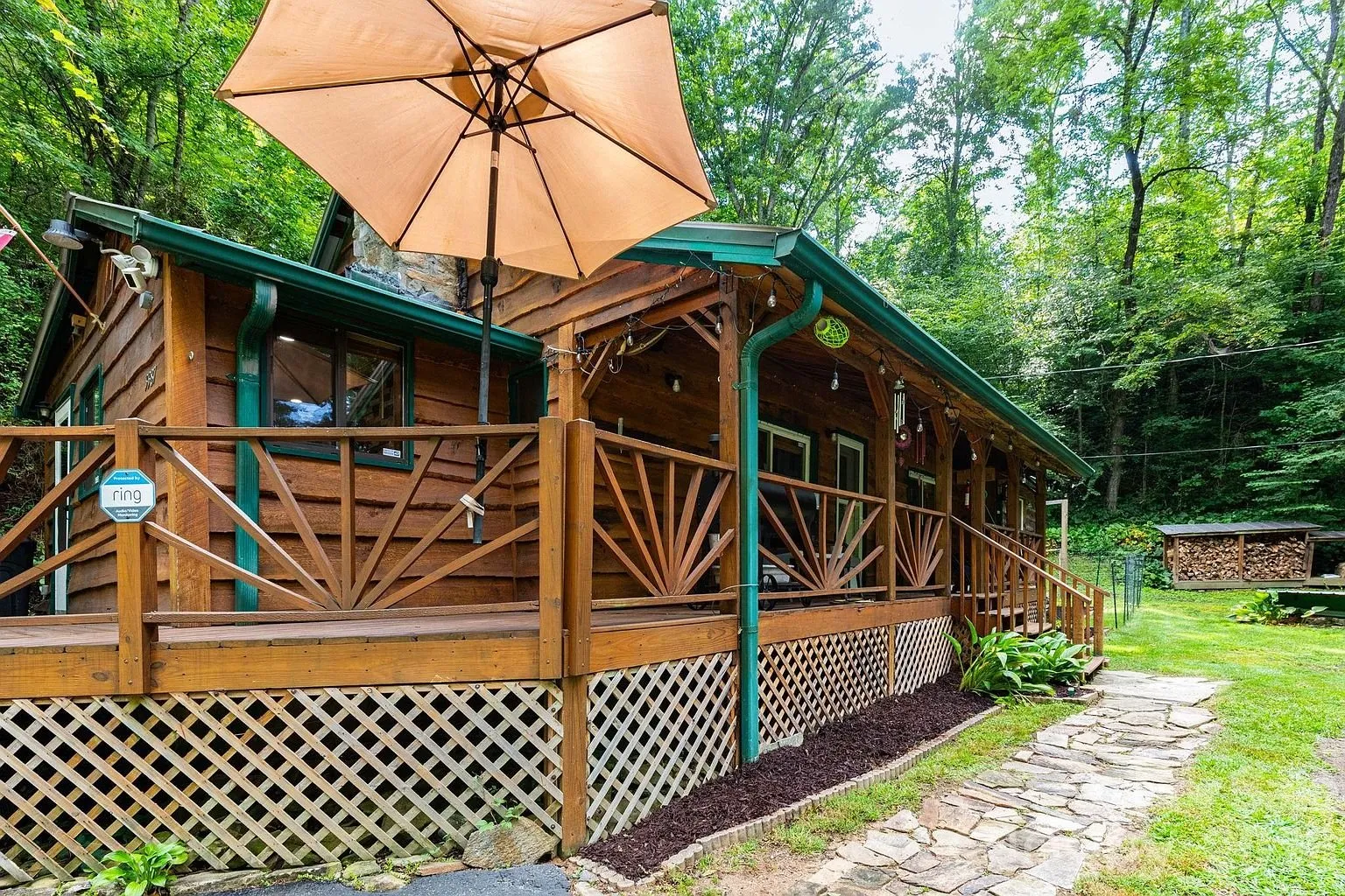 The porch corner with the umbrella and the woods behind