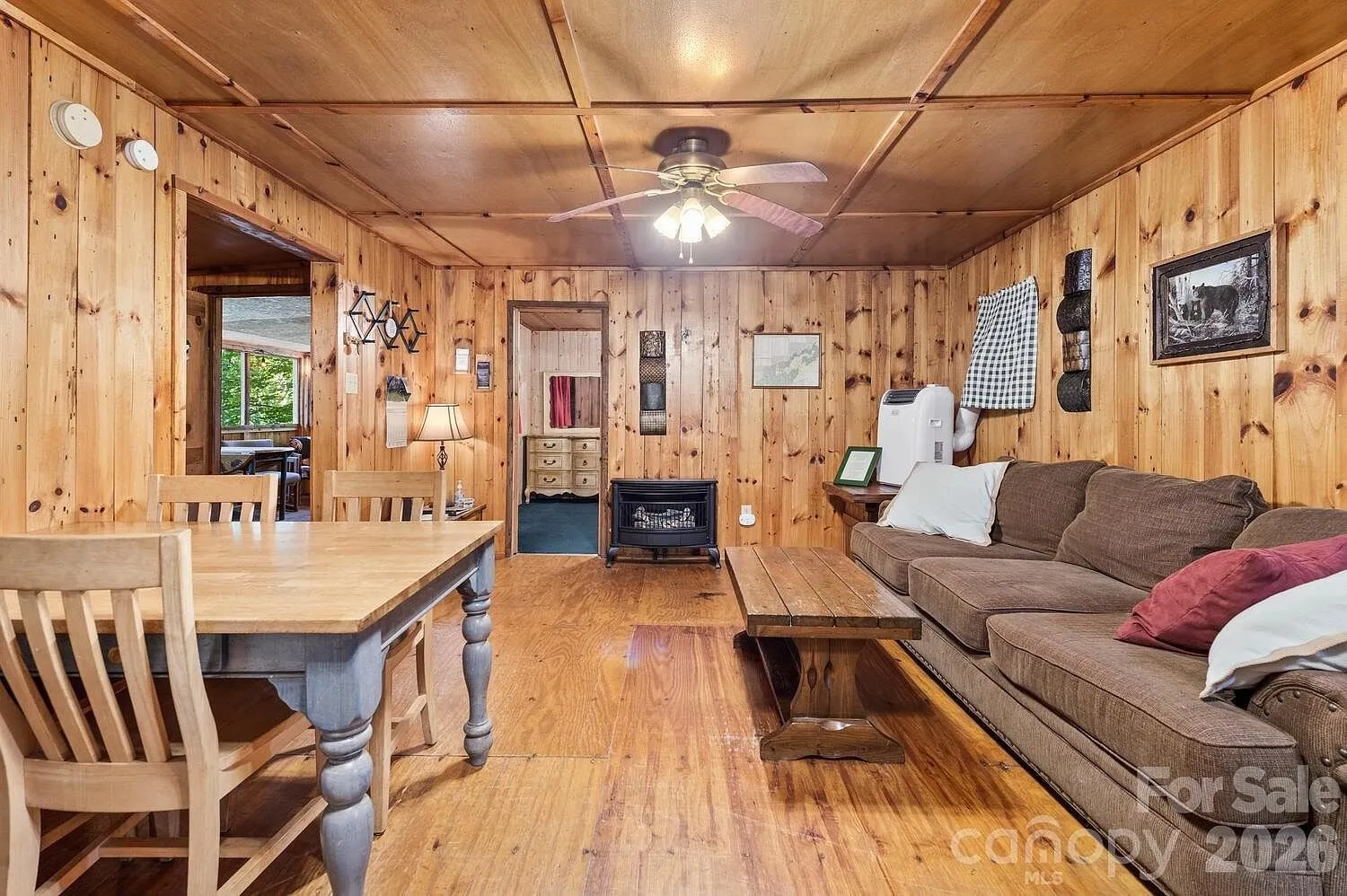 The main room with the pine walls, the sofa, the table and the ceiling fan