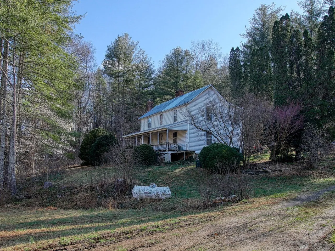 The house from the field at the side, outbuildings and a propane tank beyond
