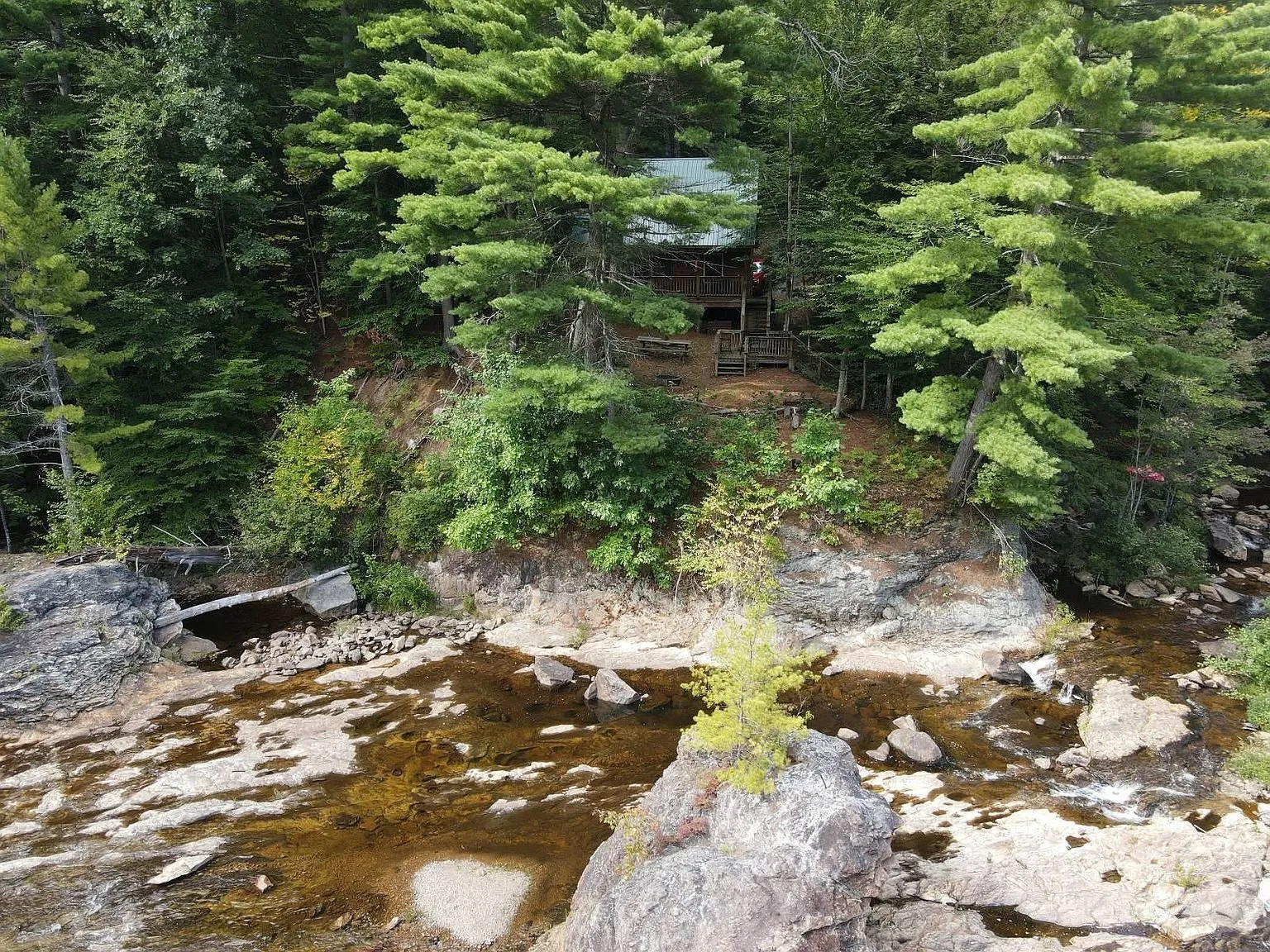 The chalet on the rise above the rock ledges of the river