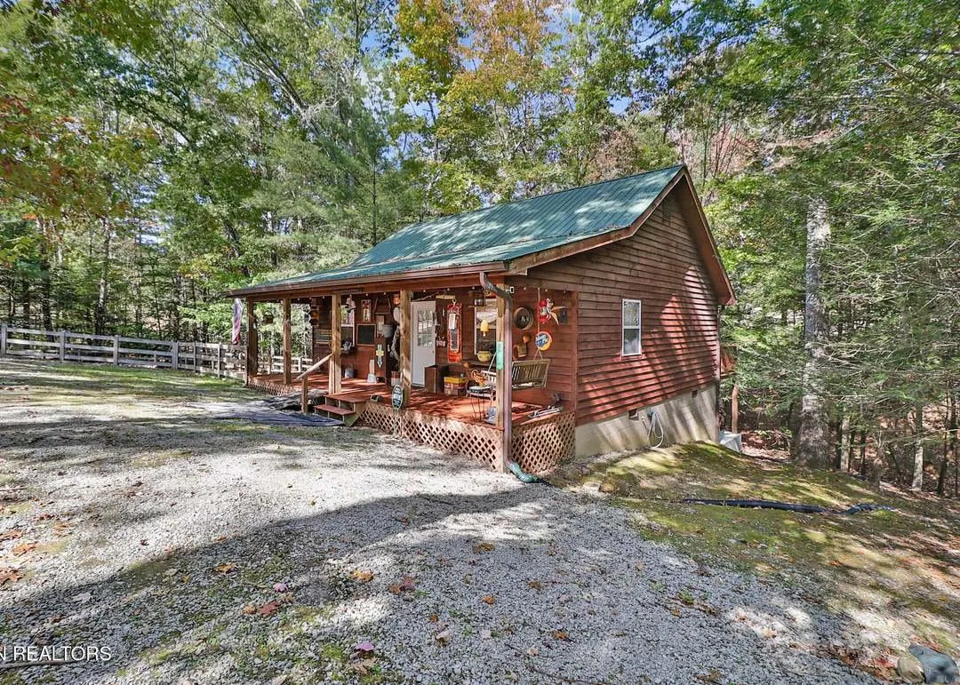 The cabin seen from the side, covered porch and open deck both visible