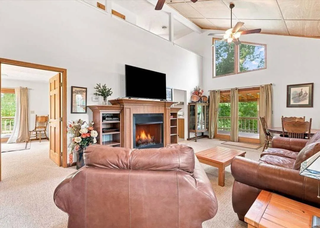 The vaulted living and dining area with a stone fireplace