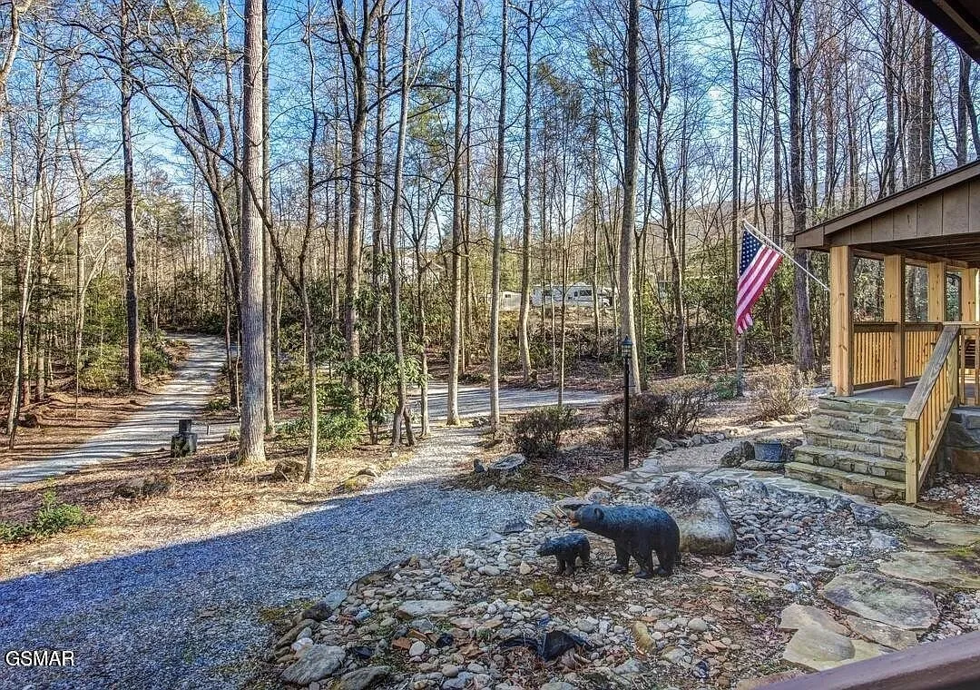 The stone walkway to the cabin with a bear statue and the flag on the porch