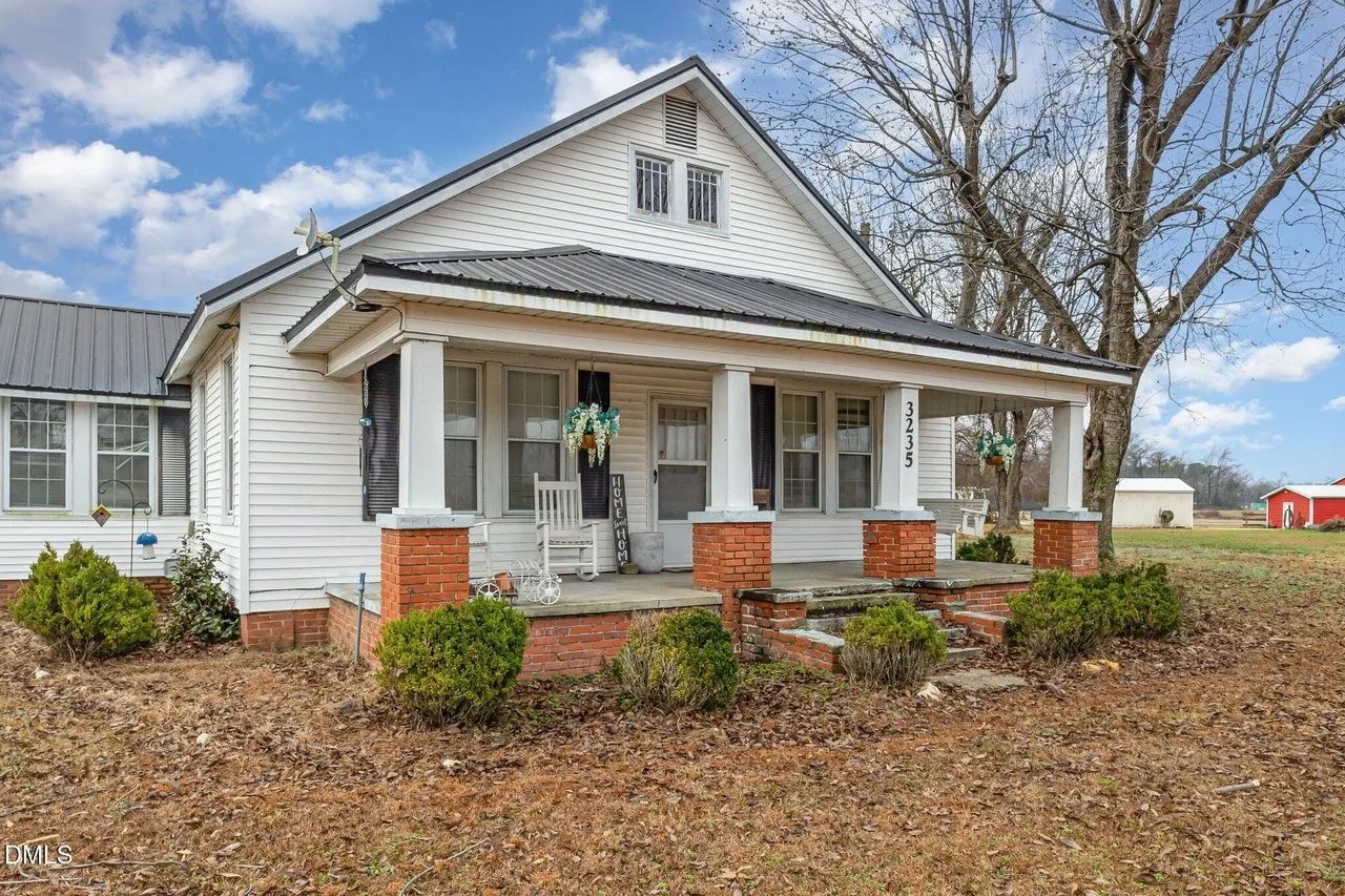 The front porch with its columns and railings, shrubs along the foundation