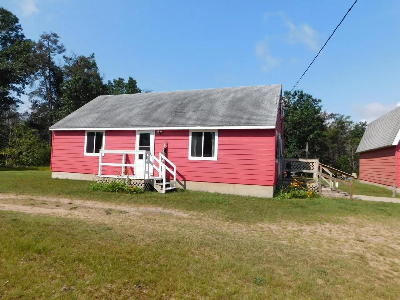 The front of the cabin with the garage behind it and pines along the lot line