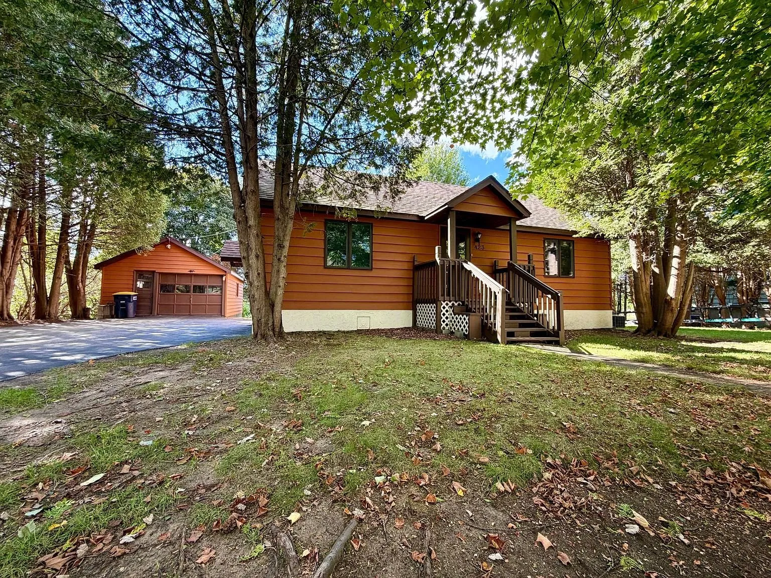 The house from the side with the garage and the tall pines