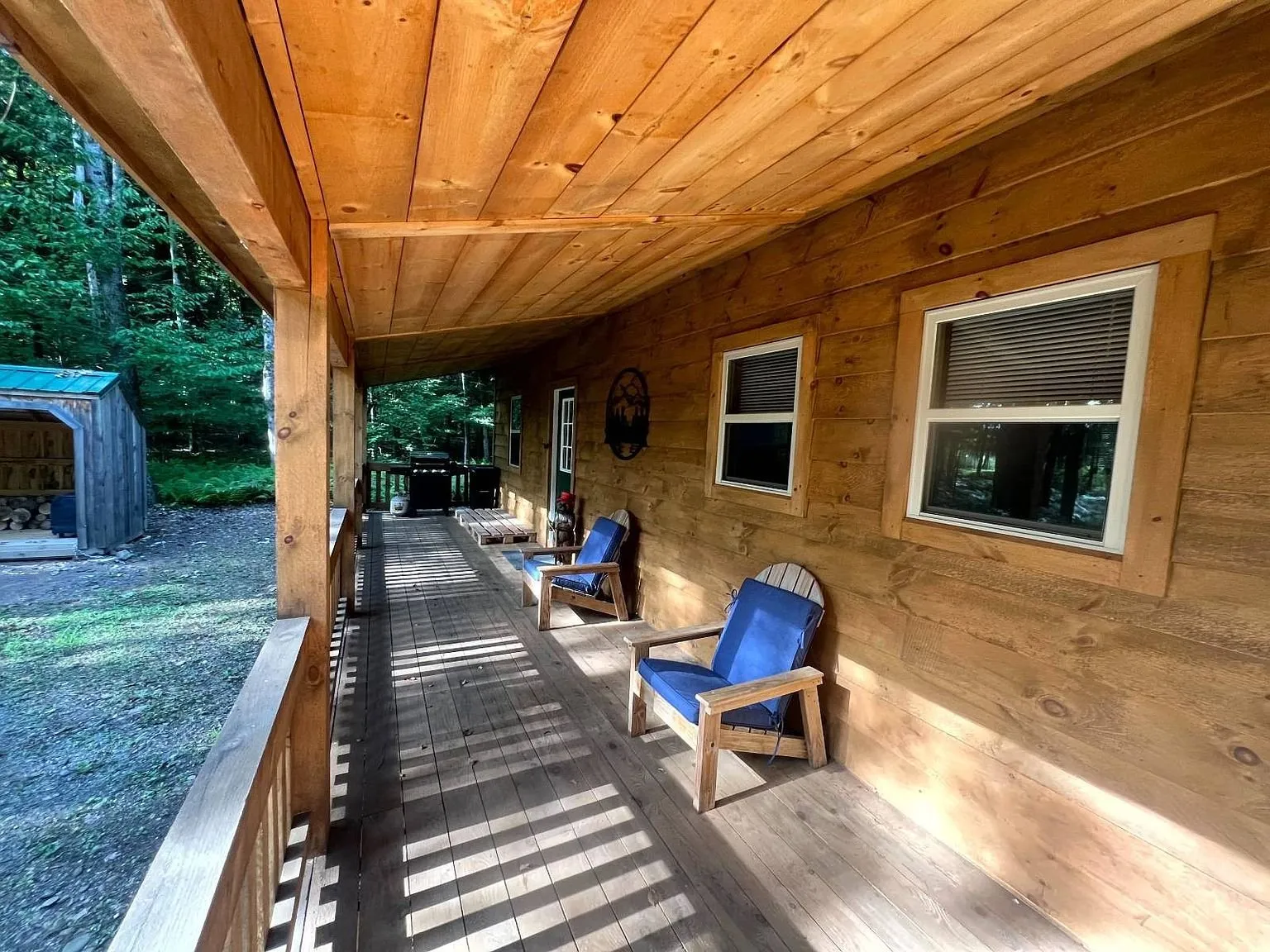 The covered porch with two chairs looking down the length of the cabin