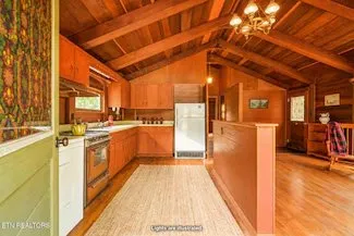 The kitchen with wood cabinets and a vaulted wood ceiling, from a virtually staged listing photo
