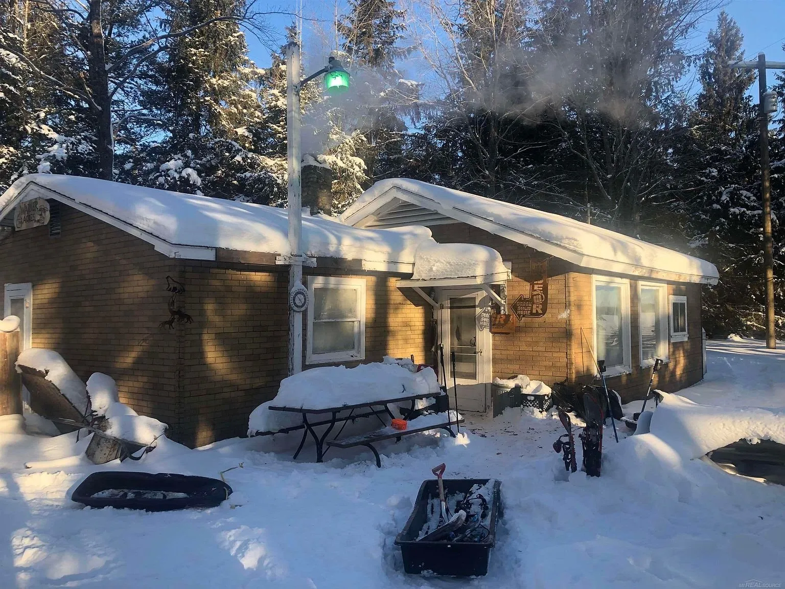The cabin under snow with the picnic table buried in the yard