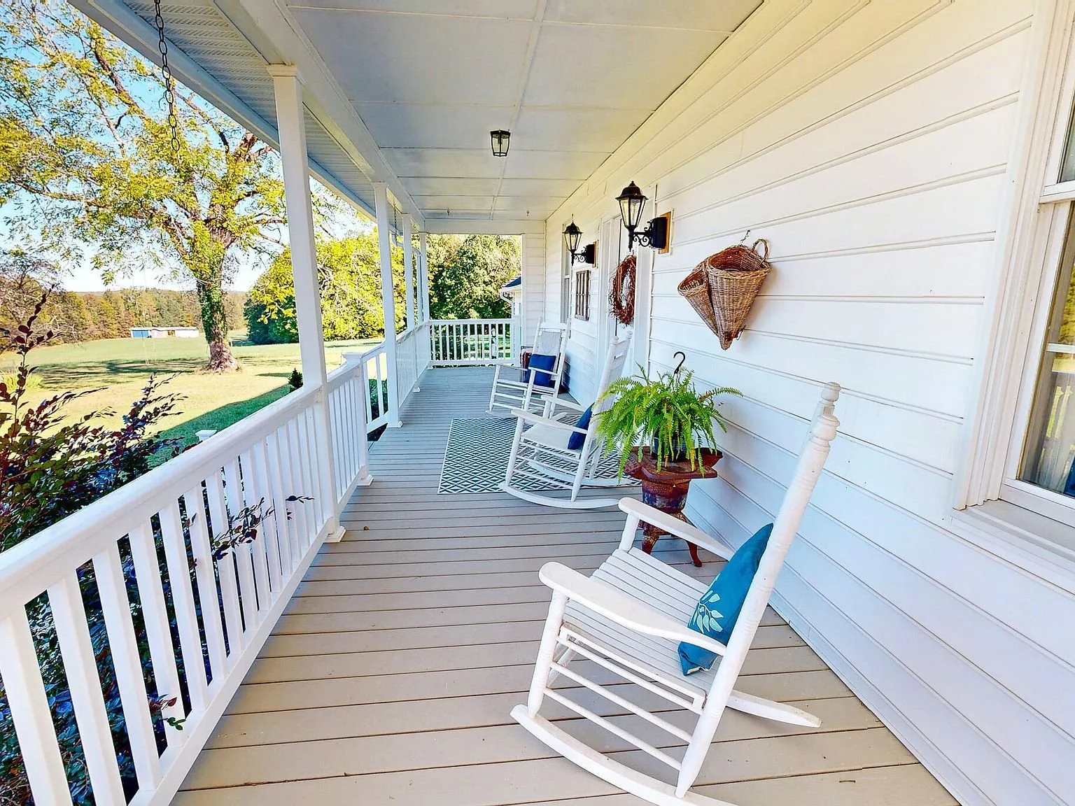 The wraparound front porch with white rocking chairs and railings