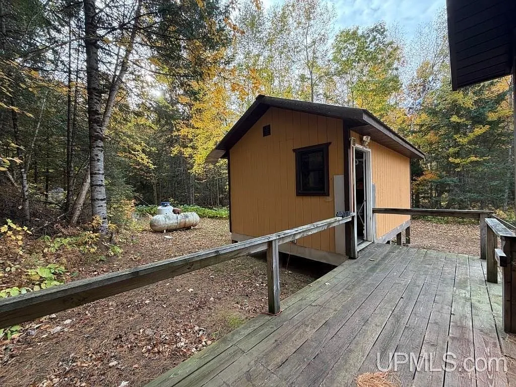 A covered ramp leading up to the cabin's entrance among the trees