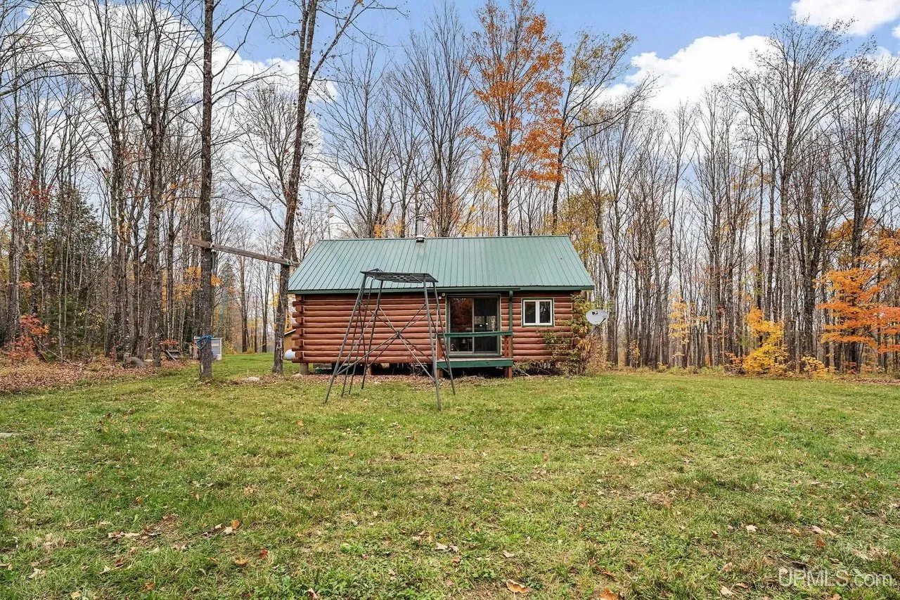 The front of the cabin from the far side of the clearing under a blue sky