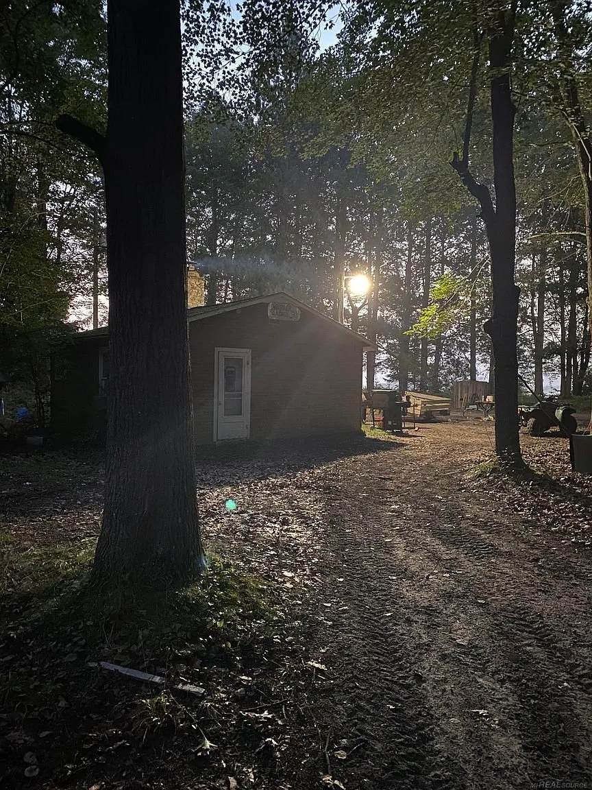 The cabin lit by a lamp at dusk with the two-track beside it