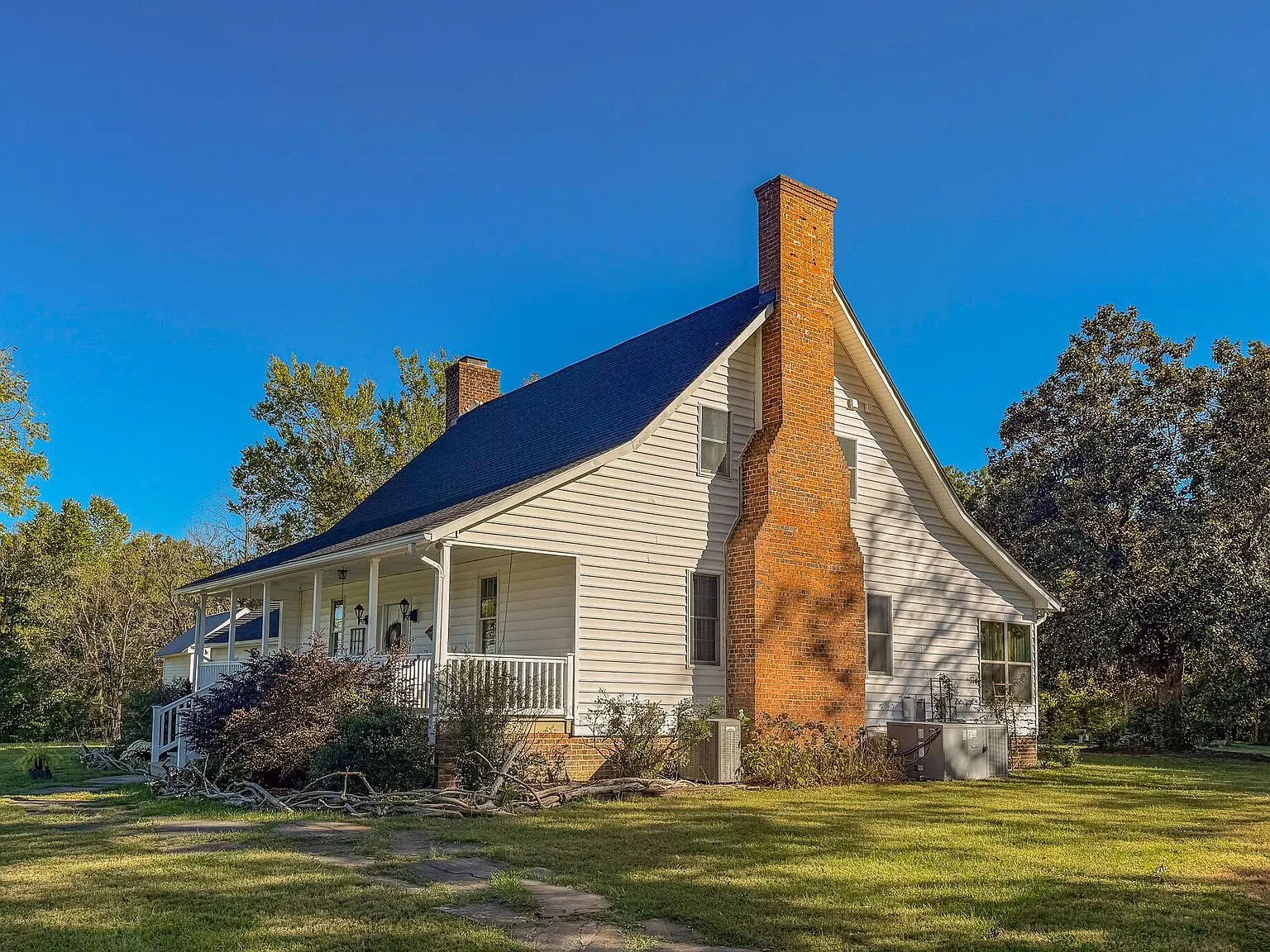 The farmhouse's rear elevation with its brick chimney against a clear sky