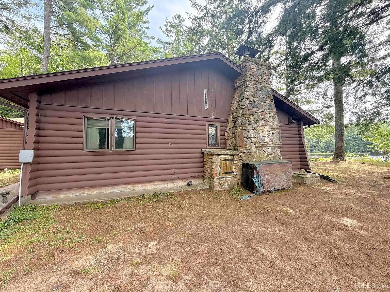 The side of the cabin with the stone chimney